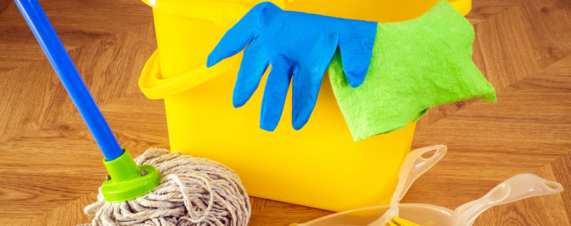 Cleaning bucket, mop and gloves on a wooden floor