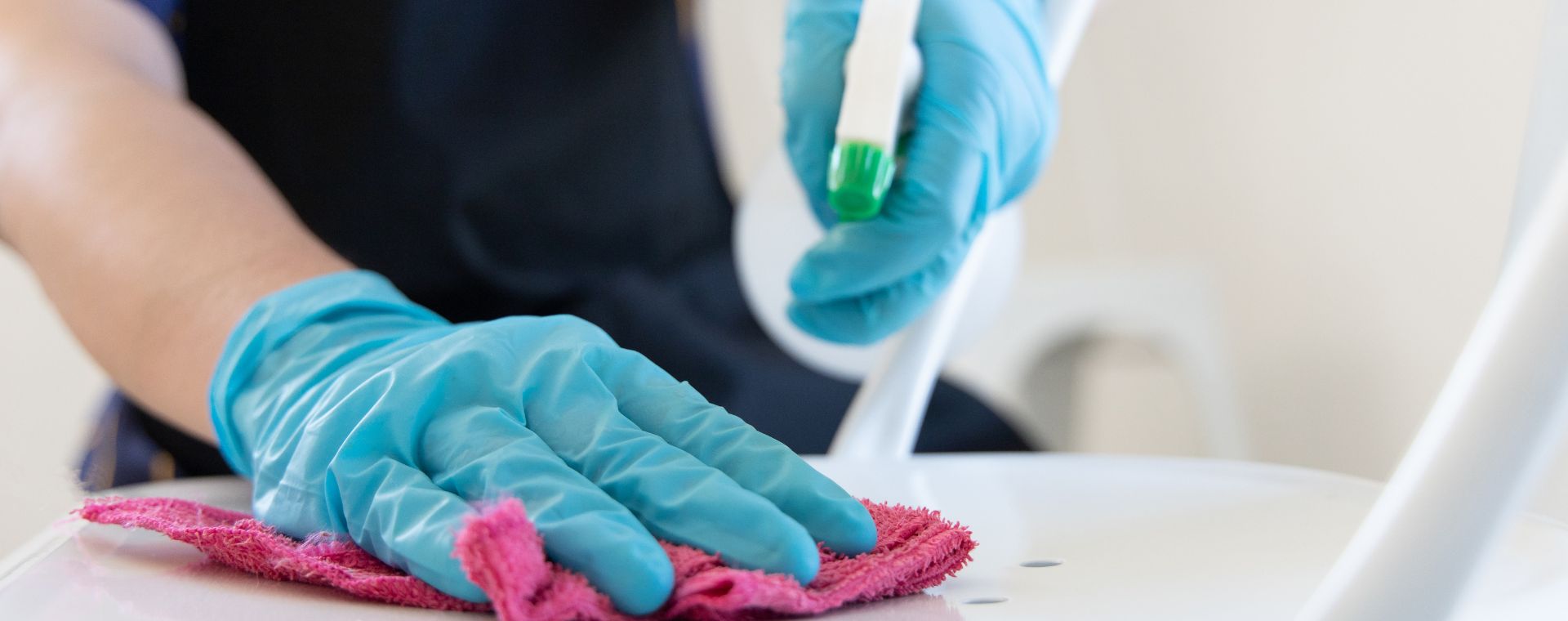 Cleaner in gloves wiping down a surface