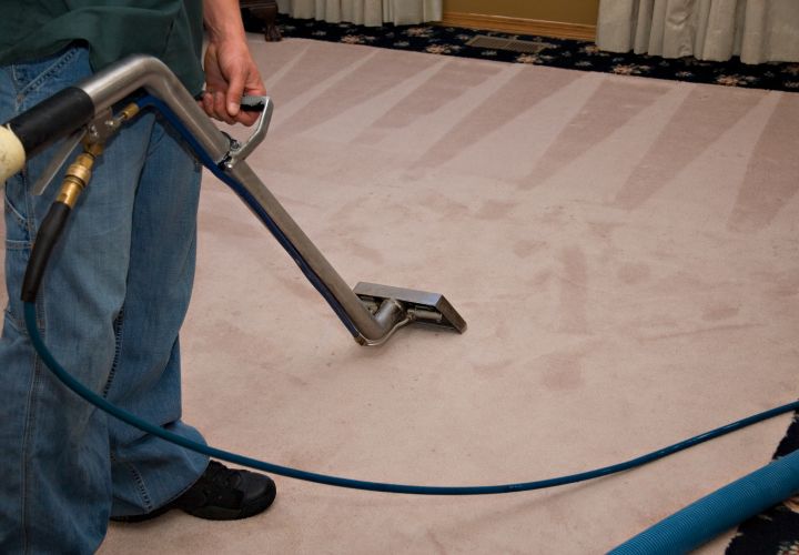 Operative deep cleaning a carpet with an extraction machine