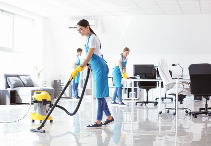 Cleaner vacuuming a bright open-plan office